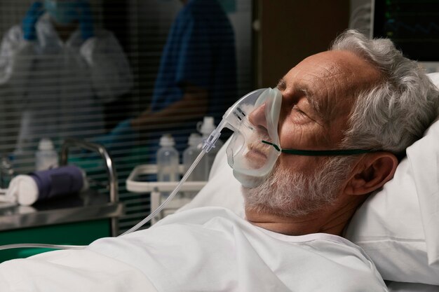 Stary człowiek z respiratorem w szpitalnym łóżku