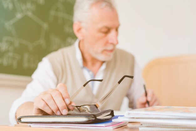 Stary profesor robi notatki w zeszycie