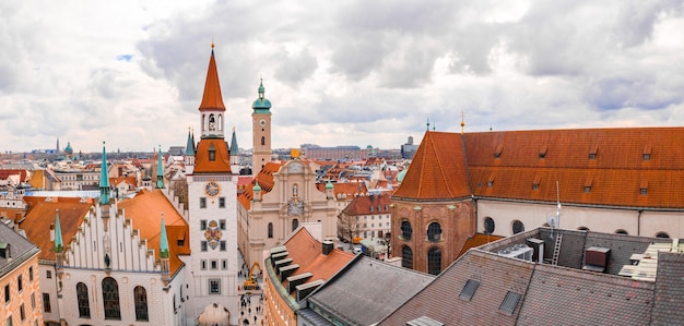 Stary Ratusz otoczony budynkami pod zachmurzonym niebem w ciągu dnia w Monachium, Niemcy