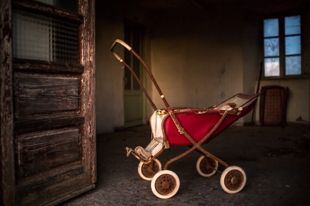 Bezpłatne zdjęcie stary zardzewiały wózek dziecięcy wewnątrz budynku z wyblakły drzwi i okna