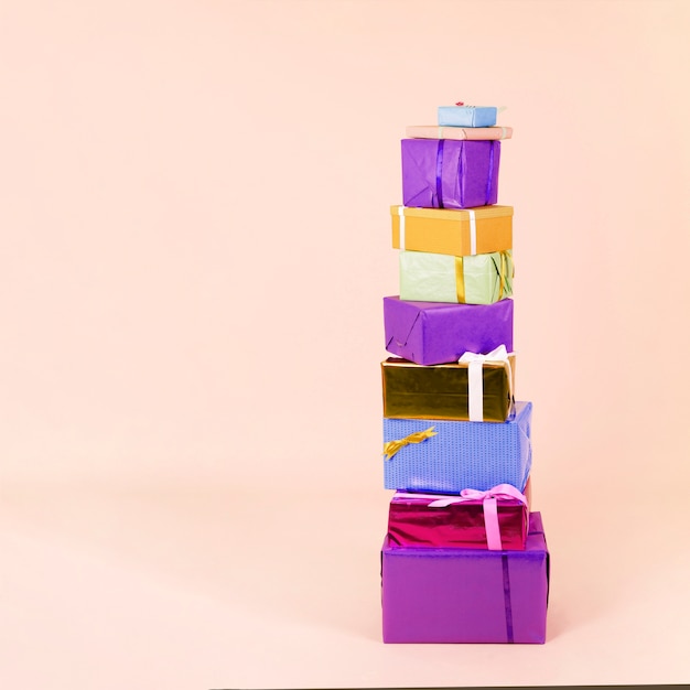Bezpłatne zdjęcie sterta kolorowi zawijający prezentów pudełka na beżowym tle