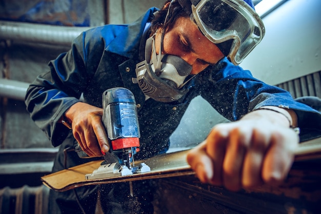 Stolarz za pomocą piły tarczowej do cięcia desek drewnianych. Szczegóły konstrukcyjne pracownika płci męskiej lub poręczny mężczyzna z elektronarzędziami