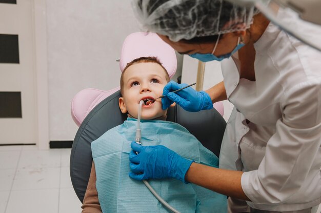 Stomatolog dziecięcy leczy próchnicę dziecka i jamę ustną chłopca siedzącego na fotelu dentystycznym podczas regularnych badań lekarskich