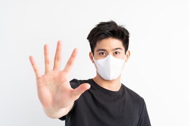 Stop Civid-19, Azjata w masce na twarzy pokazuje gest zatrzymania rąk w celu powstrzymania epidemii wirusa koronowego