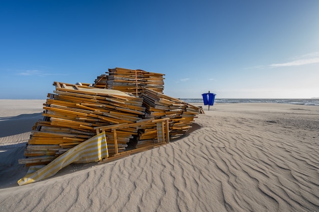 Stos nieużywanych leżaków na pustej plaży