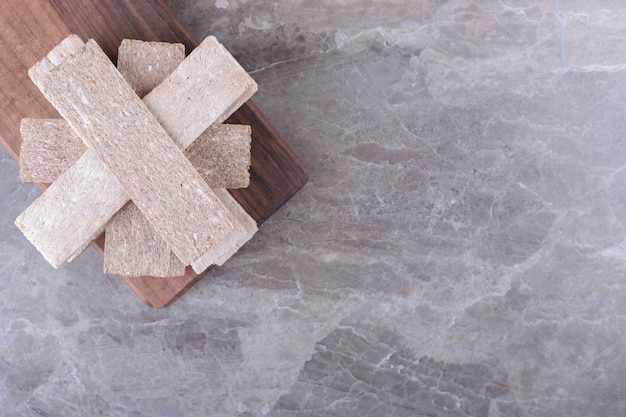Bezpłatne zdjęcie stos pieczywa chrupkiego na drewnianej desce na marmurowej powierzchni