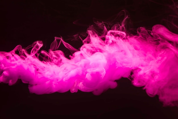 Streszczenie gęste puszyste kłęby różowego dymu na czarnym tle