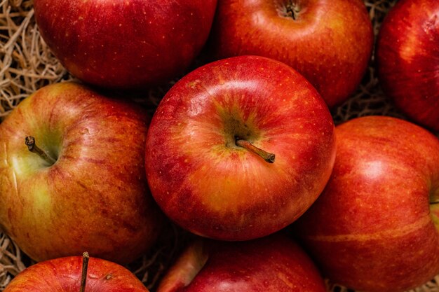 Strzał zbliżenie kilka smacznych wyglądających czerwonych jabłek na powierzchni siana