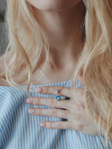 Bezpłatne zdjęcie strzał zbliżenie kobiety w niebieskiej koszuli na sobie piękny naszyjnik z ładnym wisiorkiem