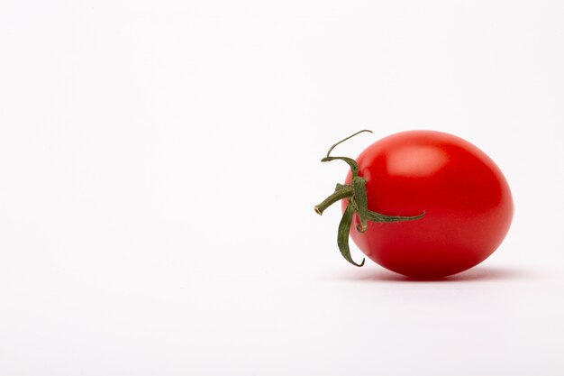 Strzał zbliżenie pomidora czereśniowego na białej ścianie - idealny na blogu o jedzeniu