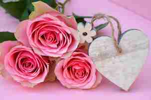Bezpłatne zdjęcie strzał zbliżenie różowe kwiaty róży z drewnianym tagiem serca z miejscem na tekst