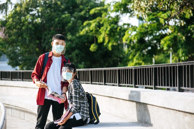 Studenci i uczennice w maskach siedzą i czytają książki na schodach