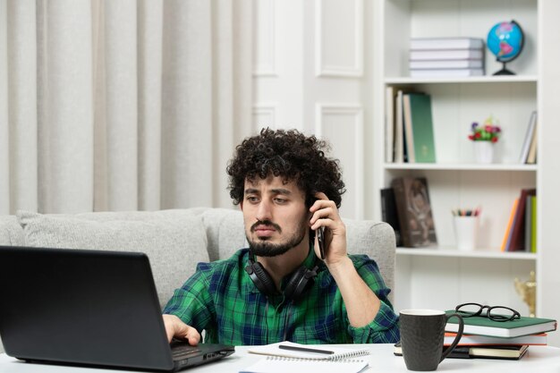 Student online ładny młody facet studiujący na komputerze w okularach w zielonej koszuli na klawiaturze pisania