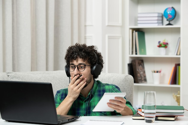 Student Online ładny Młody Facet Studiujący Na Komputerze W Okularach W Zielonej Koszuli Zakrywającej Usta