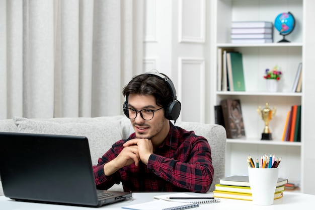 Student online młody facet w kraciastej koszuli w okularach studiujący komputer trzymający się razem za ręce