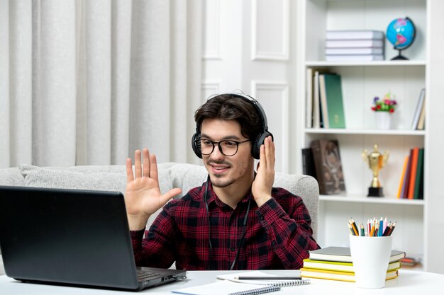Student online młody facet w kraciastej koszuli w okularach studiuje na komputerze machając rękami