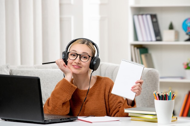 Studentka online ładna dziewczyna w okularach i swetrze studiująca na komputerze uśmiechnięta i trzymająca pióro