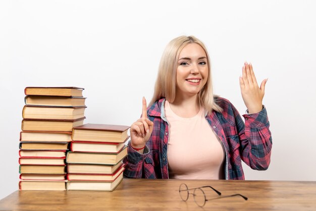 Bezpłatne zdjęcie studentka siedzi z książkami i uśmiechem na białym tle