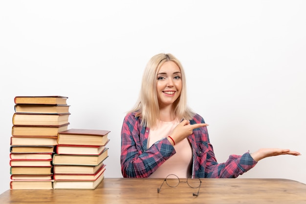 Bezpłatne zdjęcie studentka siedzi z książkami na białym tle