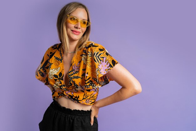 Studio bliska portret mody ładnej blond kobiety w stylowej bluzce i lnianych szortach pozowanie na fioletowym tle
