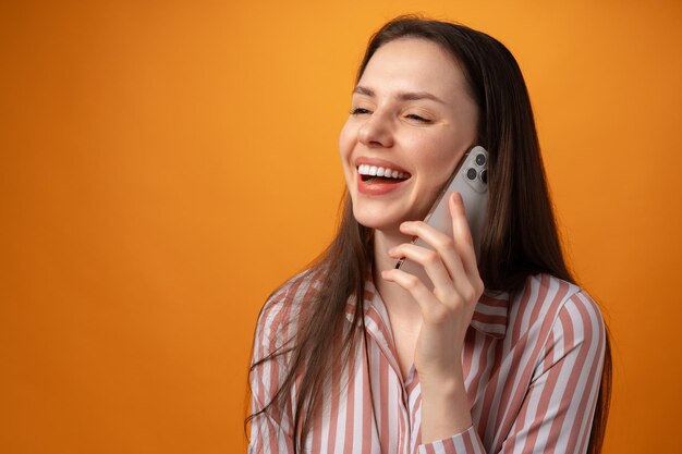 Studio fotografii młodej kobiety rozmawiającej przez telefon na żółtym tle