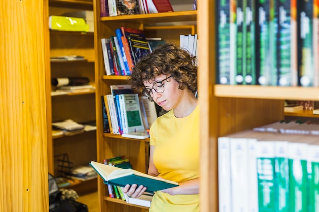 Bezpłatne zdjęcie studiowanie kobiety stojącej za regałem