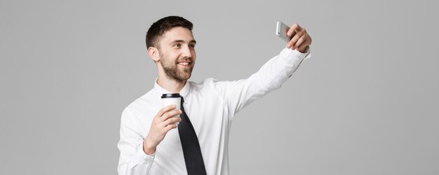 Styl życia i koncepcja biznesowa Portret przystojnego biznesmena lubi robić selfie z filiżanką kawy na wynos Odizolowane Białe tło Kopiowanie miejsca