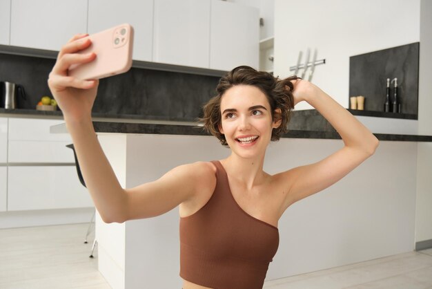 Styl życia i trening nowoczesna dziewczyna fitness robi selfie na macie do jogi, wykonuje ćwiczenia w domu i ma