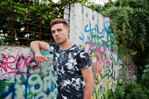 Styl życia portret przystojnego mężczyzny pozującego na ulicy miasta ze ścianą graffiti