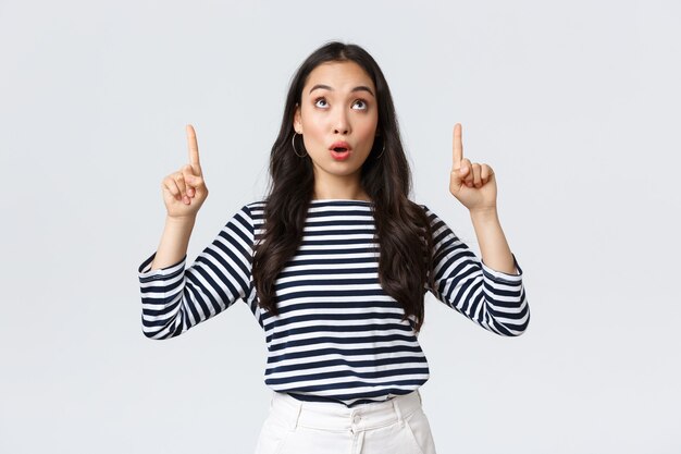 Styl życia, uroda i moda, koncepcja emocji ludzi. Zaskoczona i zaintrygowana atrakcyjna koreańska dziewczyna robi zakupy, znalazła dobrą wyprzedaż, wskazując palcem na górny baner i mówiąc wow