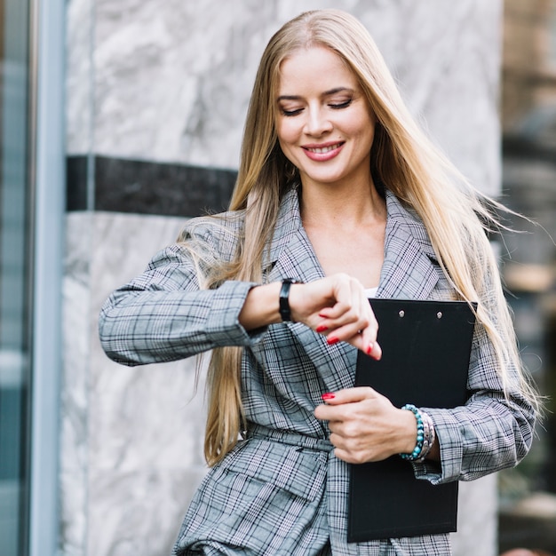 Bezpłatne zdjęcie stylowa bizneswoman patrząc na zegarek