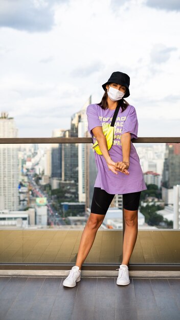 Stylowa kaukaska kobieta w modnej panamie i neonowej torebce na talii na dachu w Bangkoku