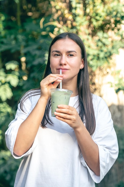 Bezpłatne zdjęcie stylowa kobieta pije matcha latte w parku