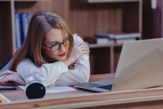 Stylowa kobieta pracuje przy biurku na laptopa w nowoczesnym biurze