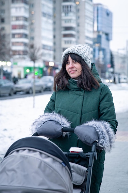 Stylowa młoda mama na spacer z dzieckiem w wózku zimą