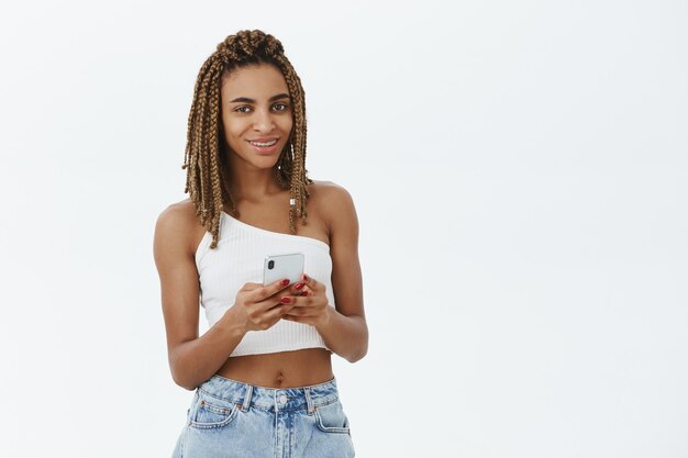 Stylowa, nowoczesna dziewczyna afroamerykańska za pomocą smartfona