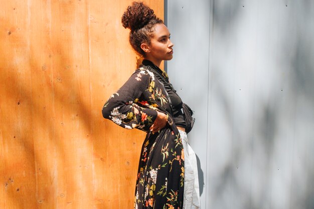 Bezpłatne zdjęcie stylowa nowożytna kobieta pozuje blisko ściennego przyglądającego outside