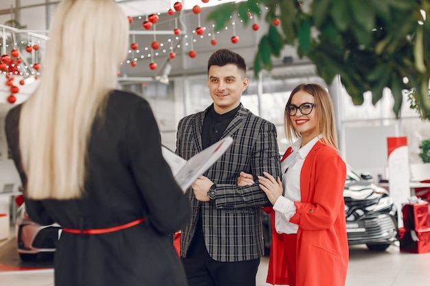 Bezpłatne zdjęcie stylowi i eleganccy ludzie w salonie samochodowym