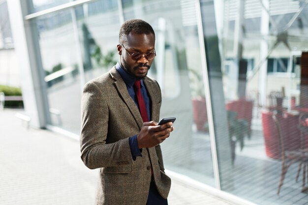 Stylowy African American czarny biznesmen działa na jego smartphone