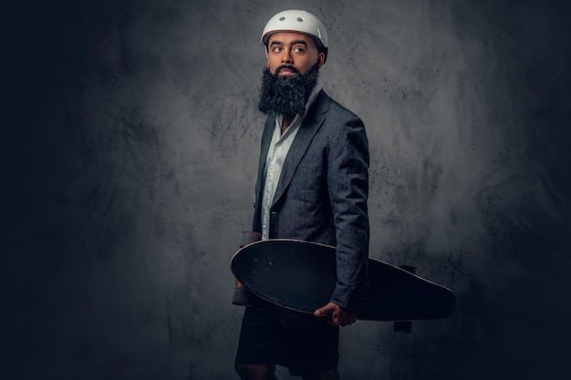 Bezpłatne zdjęcie stylowy arabski mężczyzna ubrany w szary garnitur trzyma długą deskę.