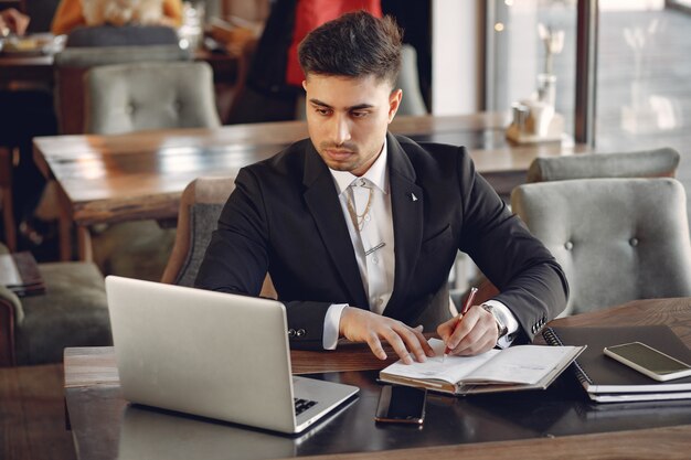 Stylowy biznesmen pracuje w kawiarni i korzysta z laptopa