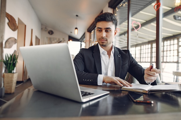 Stylowy biznesmen pracuje w kawiarni i korzysta z laptopa