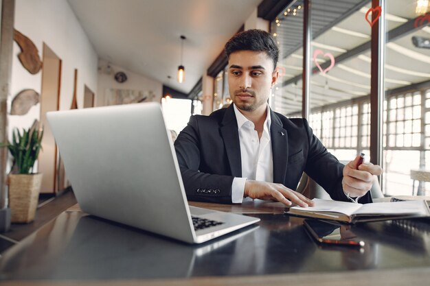 Stylowy biznesmen pracuje w kawiarni i korzysta z laptopa