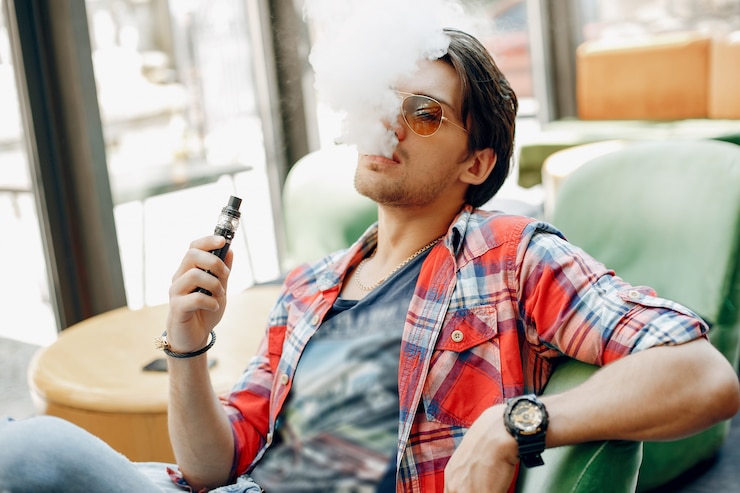 Bezpłatny plik Zdjęcie stylowy i elegancki mężczyzna siedzący w kawiarni z vape