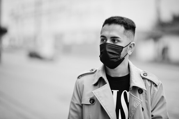 Stylowy kuwejcki mężczyzna w trenczu nosi czarną maskę podczas pandemii