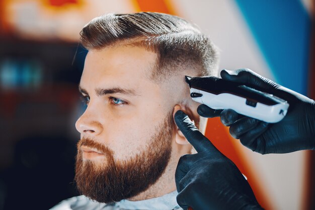 Stylowy mężczyzna siedzi w zakładzie fryzjerskim
