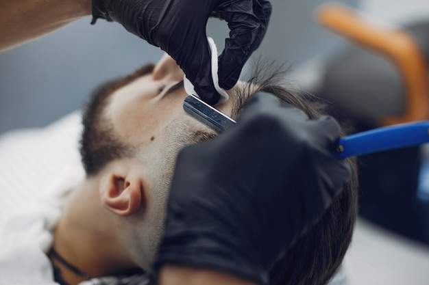 Bezpłatne zdjęcie stylowy mężczyzna siedzi w zakładzie fryzjerskim