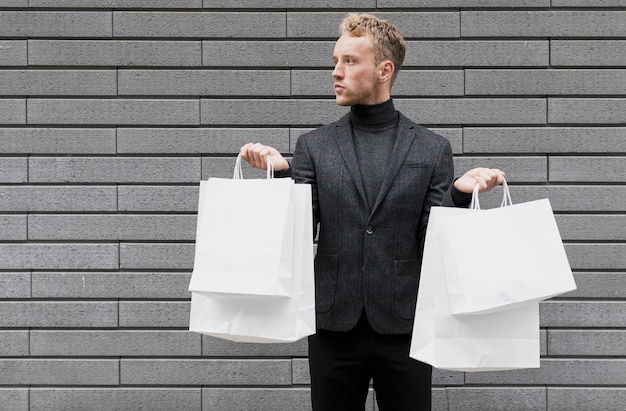 Bezpłatne zdjęcie stylowy mężczyzna z torby na zakupy w obu rękach