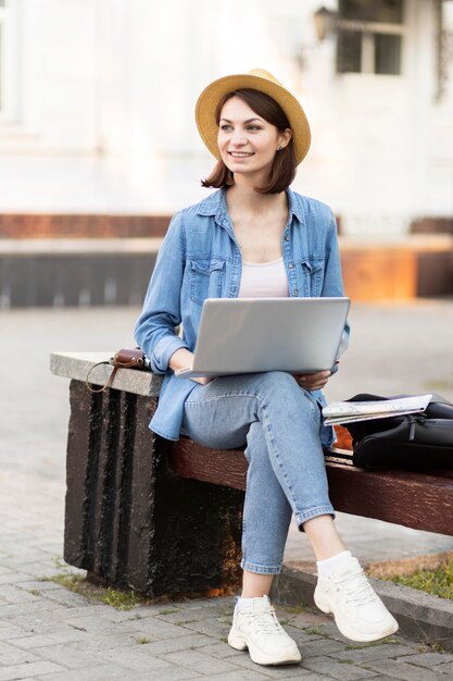 Stylowy turysta w kapeluszu gospodarstwa laptopa na zewnątrz