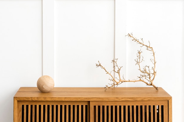 Bezpłatne zdjęcie sucha gałązka na drewnianej szafce w białym pokoju